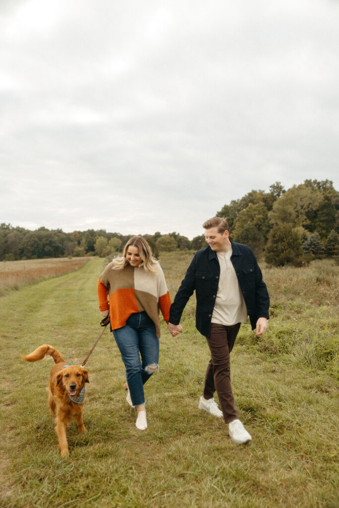 Couple walking with their dog during their Michigan engagement photos
