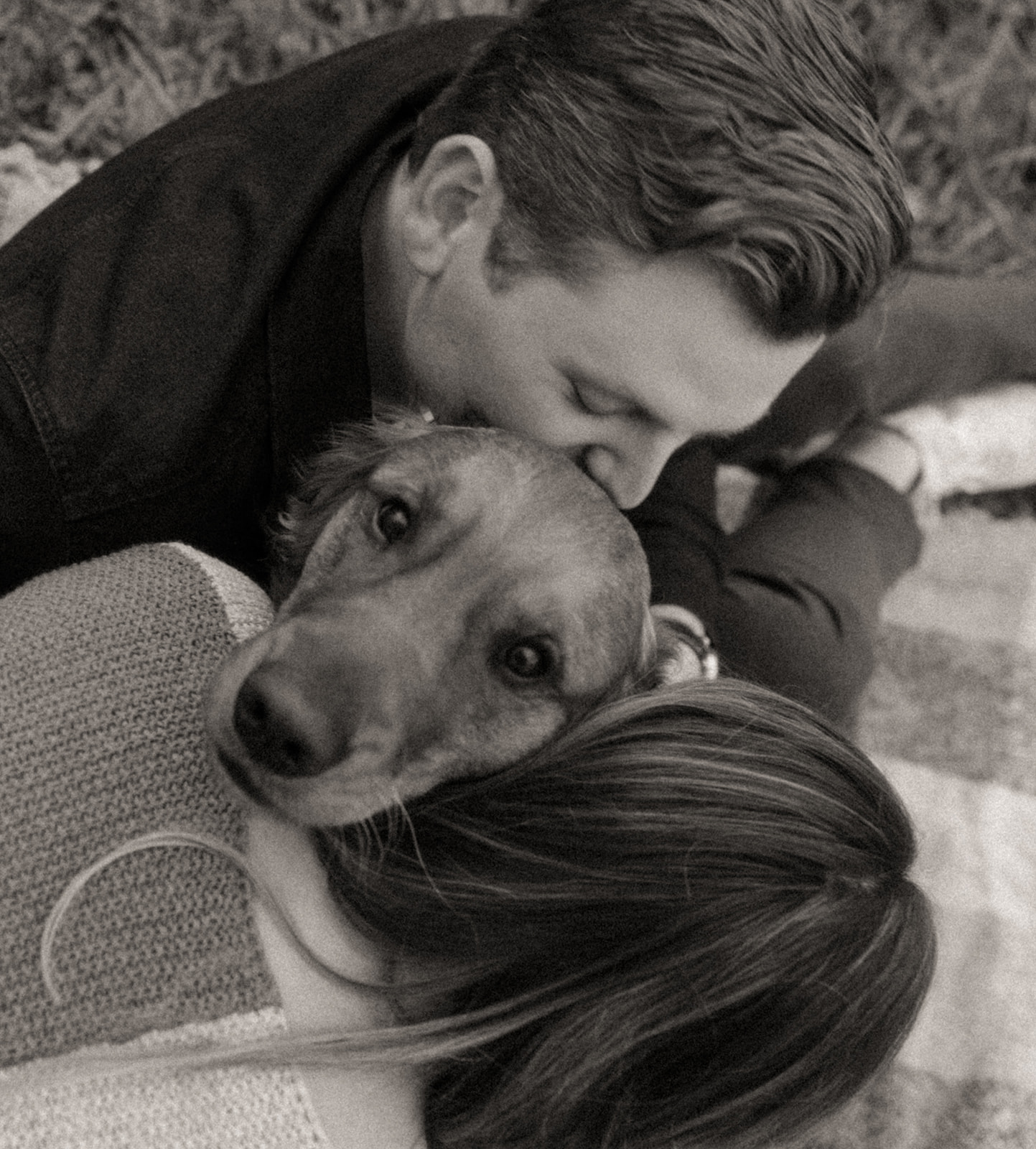 Black and white photos of a couple kissing their dog during their engagement session