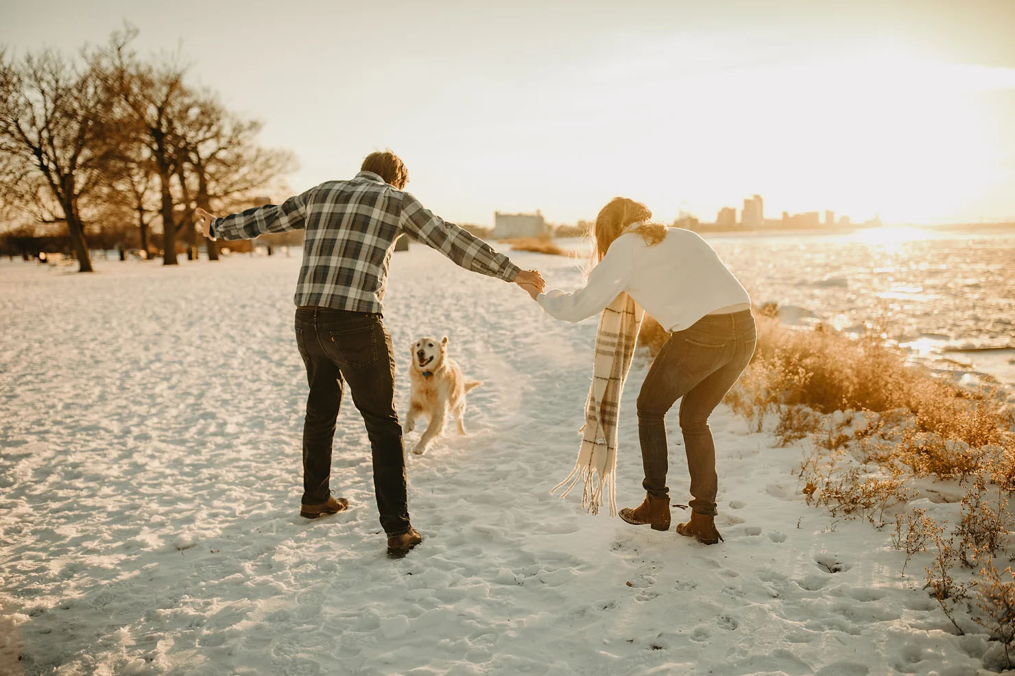 Couple playing in the snow with their dog for their Michigan engagement photos