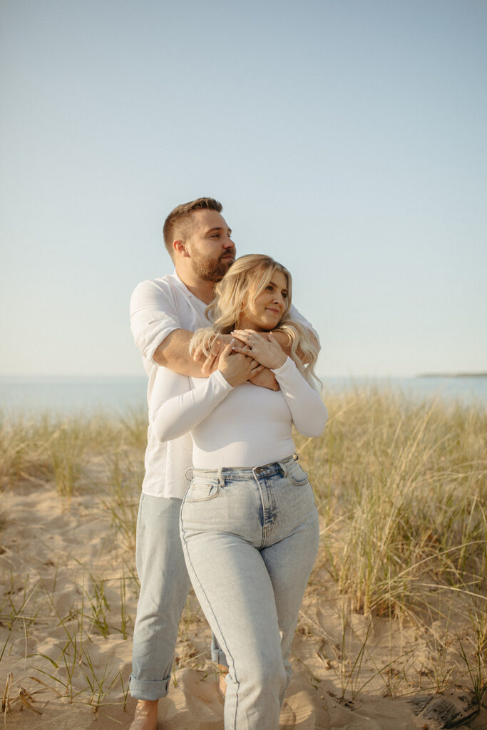 Couple posing for photos during their Michigan beach engagement photos at Sleeper State Park