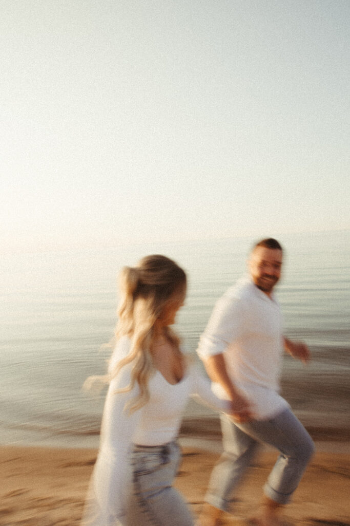 Blurry photo of couple running during their Michigan beach engagement photos at Sleeper State Park