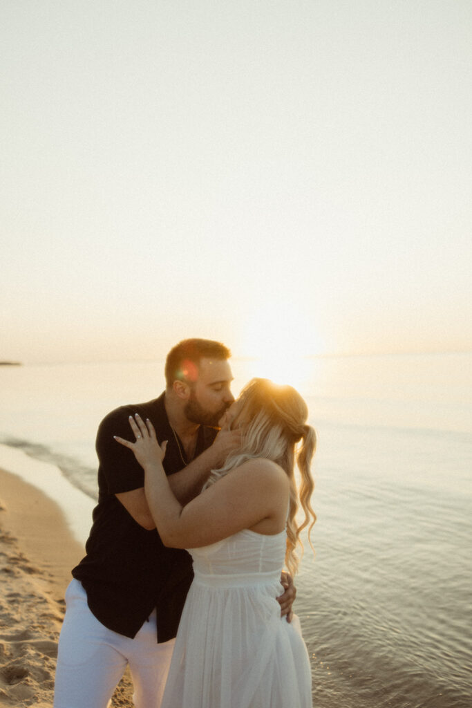 Couple kissing during their Michigan beach engagement photos during sunset