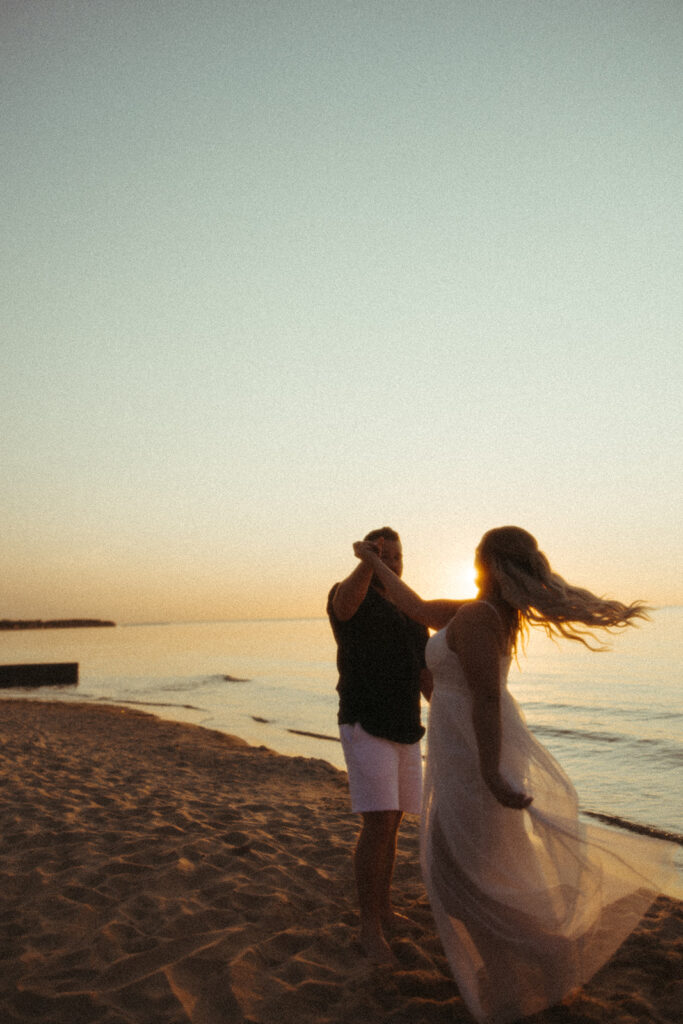 Couple dancing on the beach during sunset 
