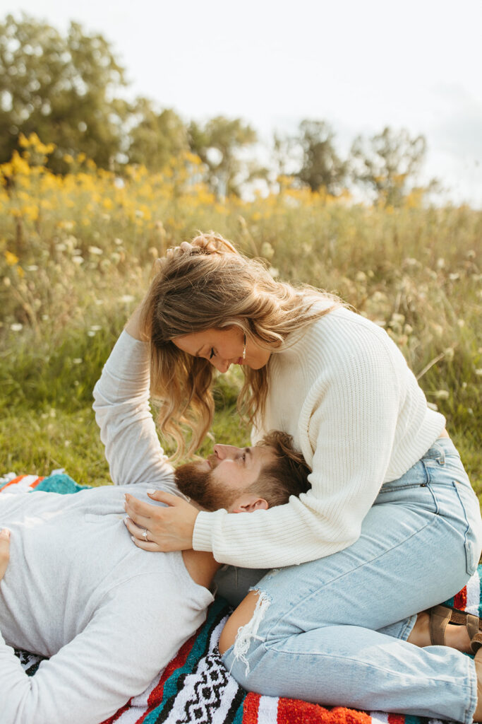 Couple sitting on a blanket in a field for their photoshoot