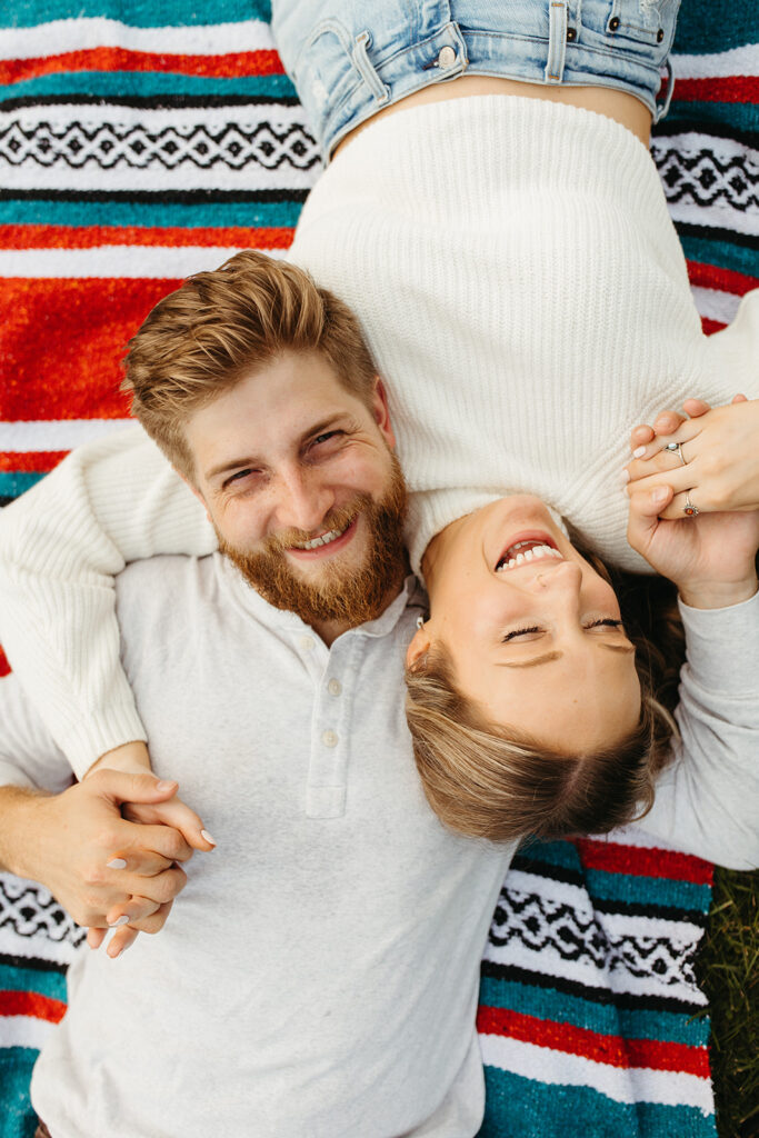 Couples laying on a blanket and laughing during their session