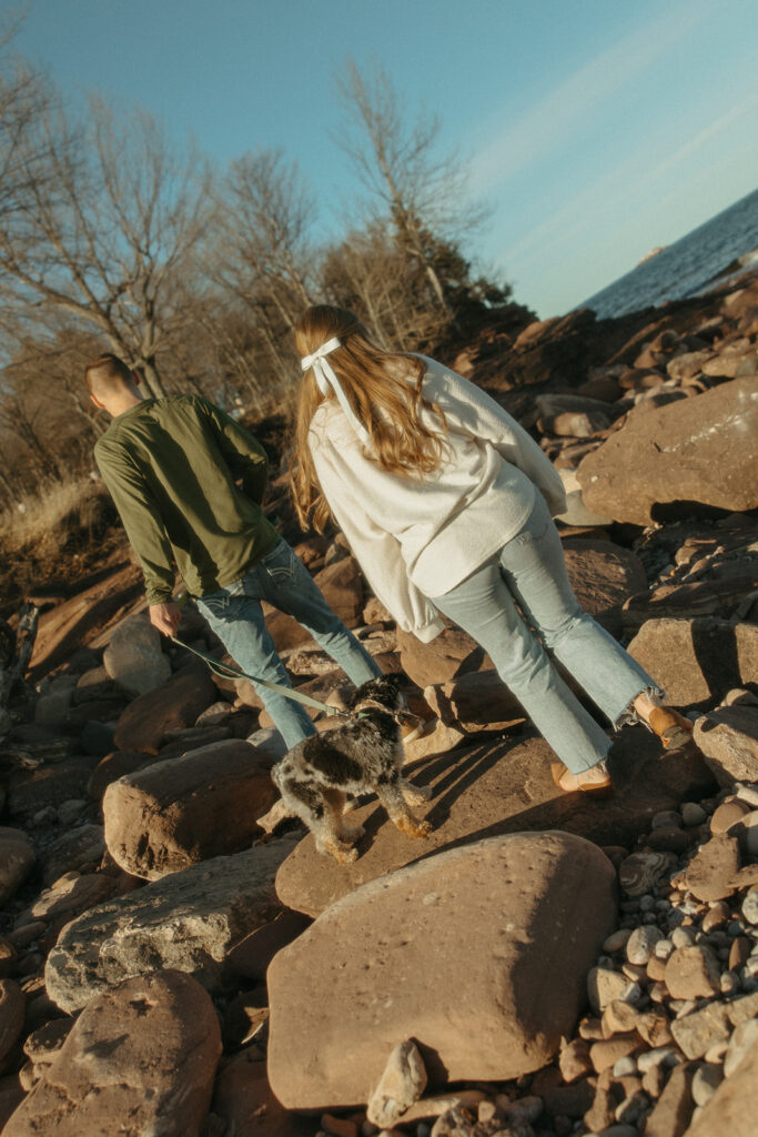 Couple and their dog walking the rocks for their Marquette Michigan engagement photos