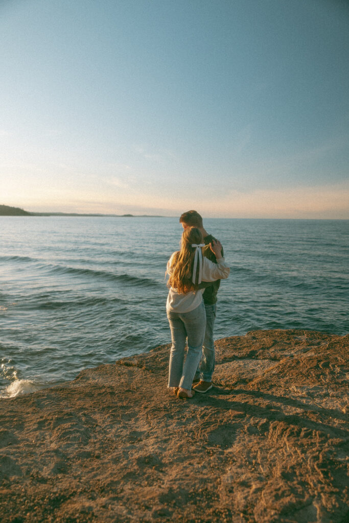 Man and woman admiring Lake Superiors during their Marquette Michigan engagement photos