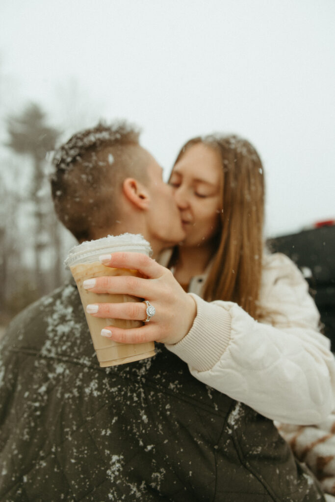 Man and woman kissing as woman holds an iced coffee in her hands