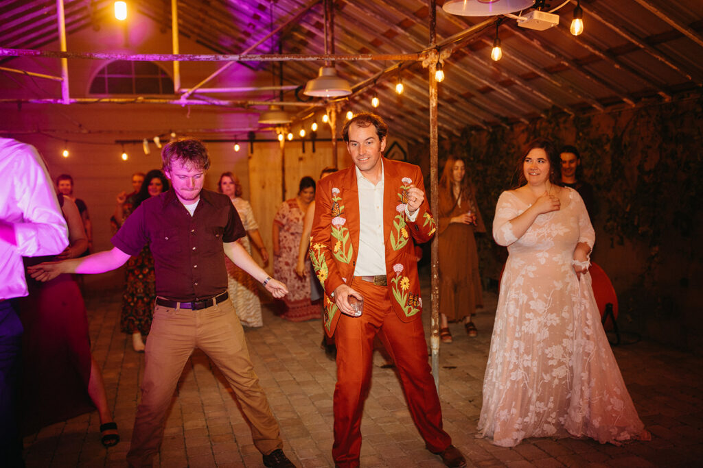 Bride, groom and wedding guest dancing