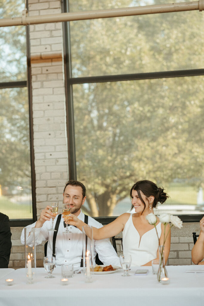 Bride and groom toasting drinks during the speeches Baker Lofts Holland MI wedding reception