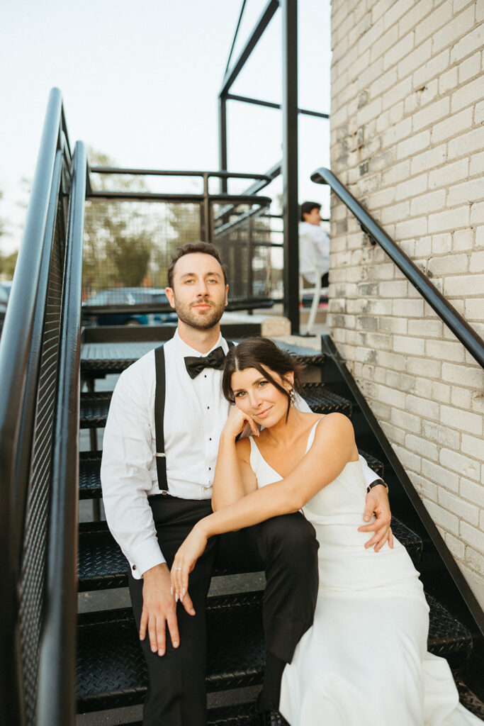 Bride and groom sitting on the stairs of Baker Lofts Holland Michigan wedding even venue