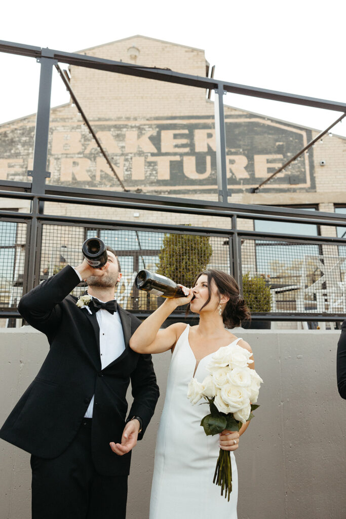 Bride and groom drinking champagne from the bottle during their Baker Lofts Holland MI wedding reception