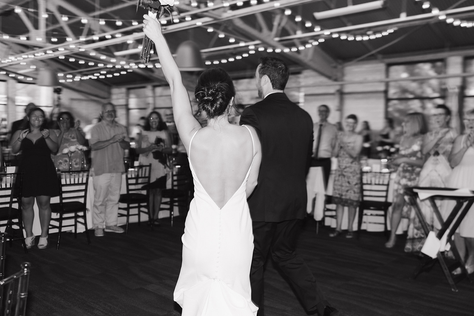 Black and white photo of a bride and groom entering their Baker Lofts Holland MI wedding reception