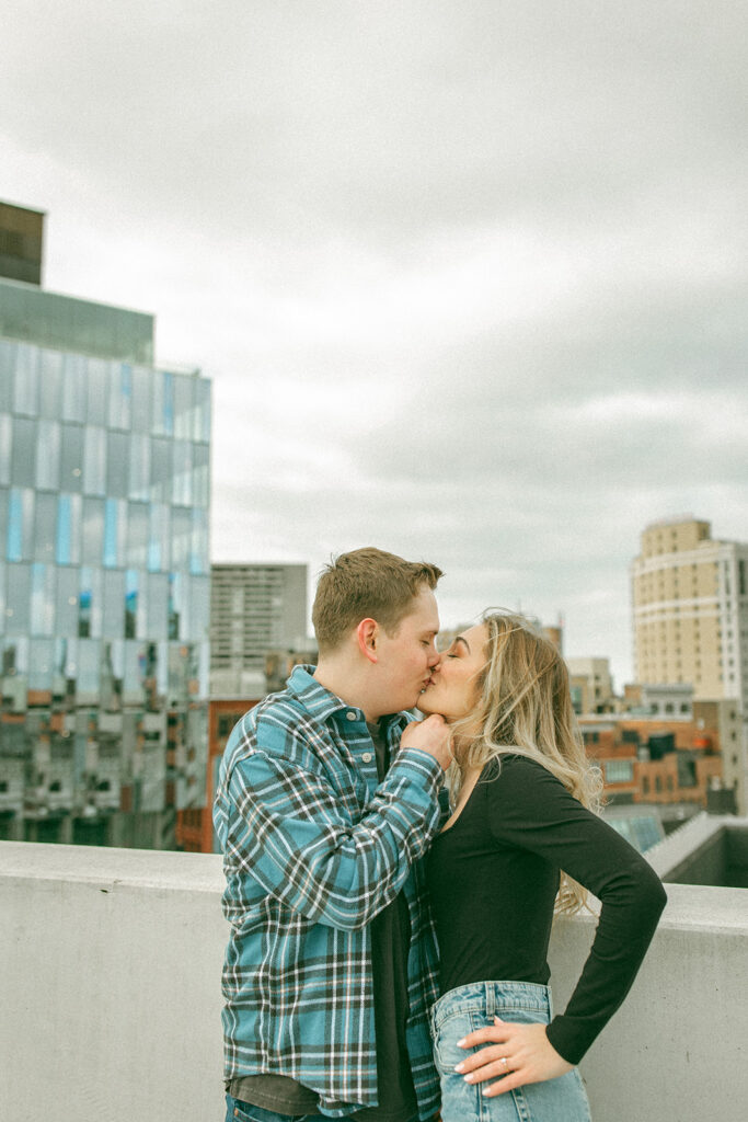 Couple kissing up on a parking garage rooftop for their downtown Detroit engagement photos at Z Lot
