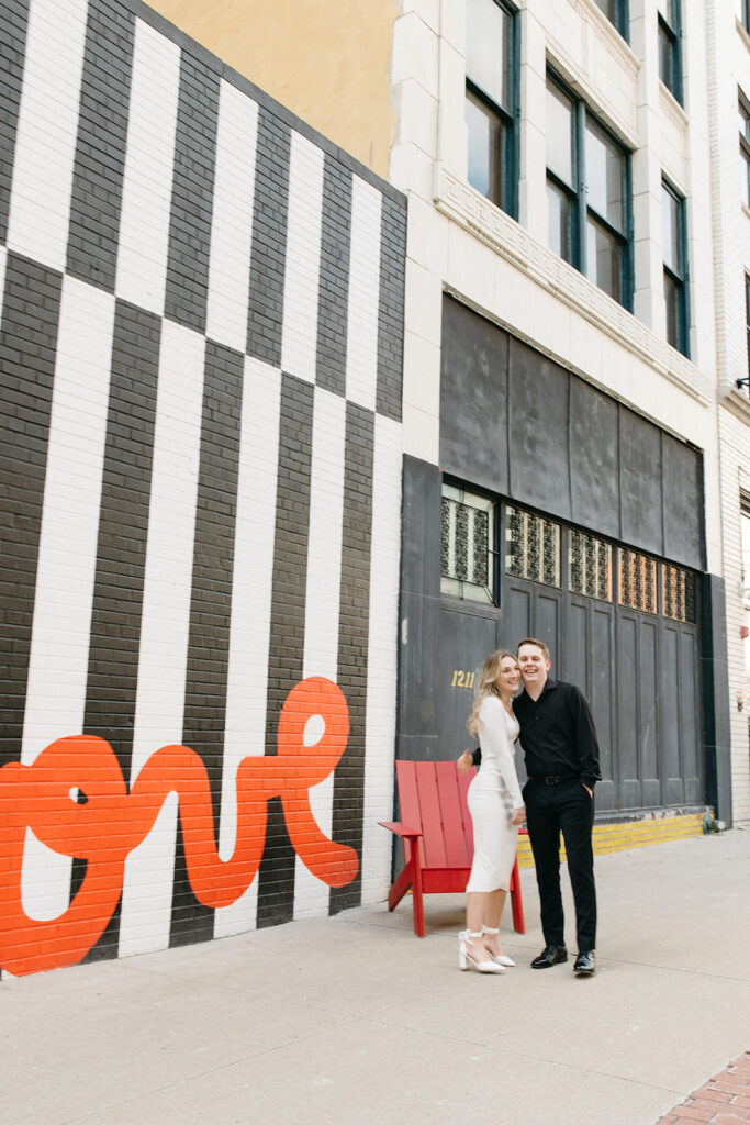 Couple posing for photos next to a love mural in downtown Detroit