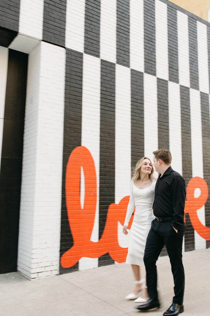 Couple walking in downtown Detroit next to a love mural