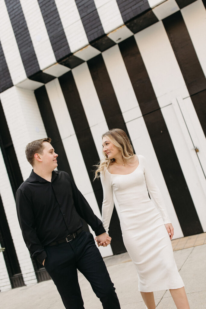 Couple walking downtown with the backdrop of a black and white striped wall