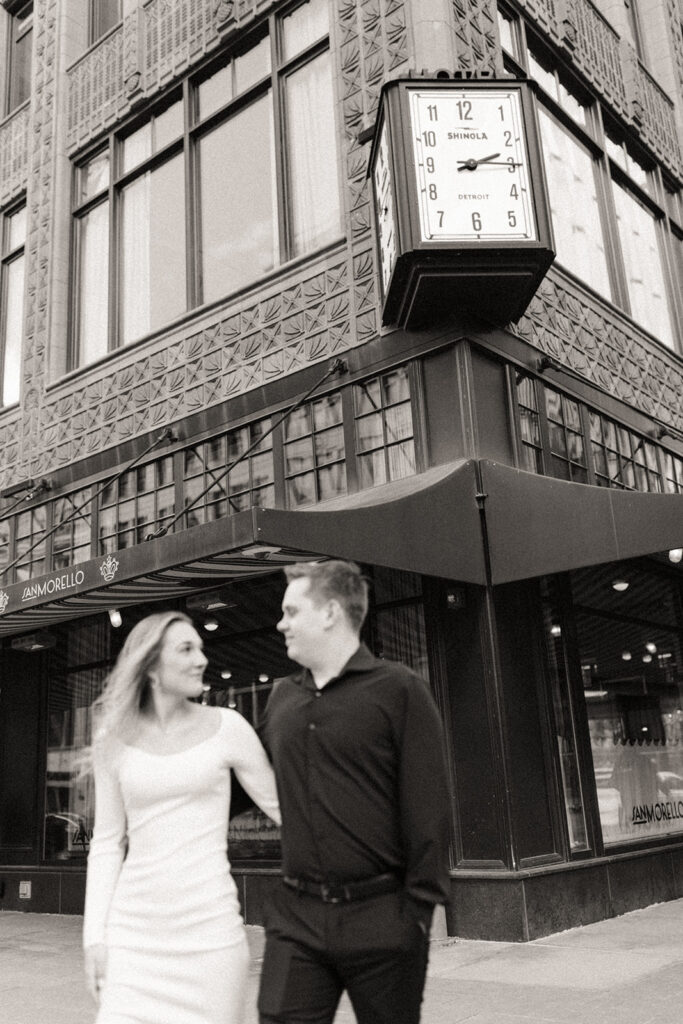 Black and white photo of a couple walking in downtown Detroit for their engagement photos
