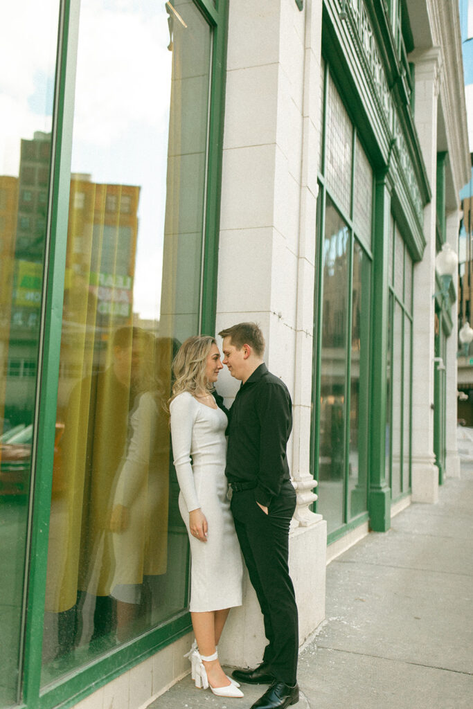 Man and woman leaning up against a shop window in downtown Detroit