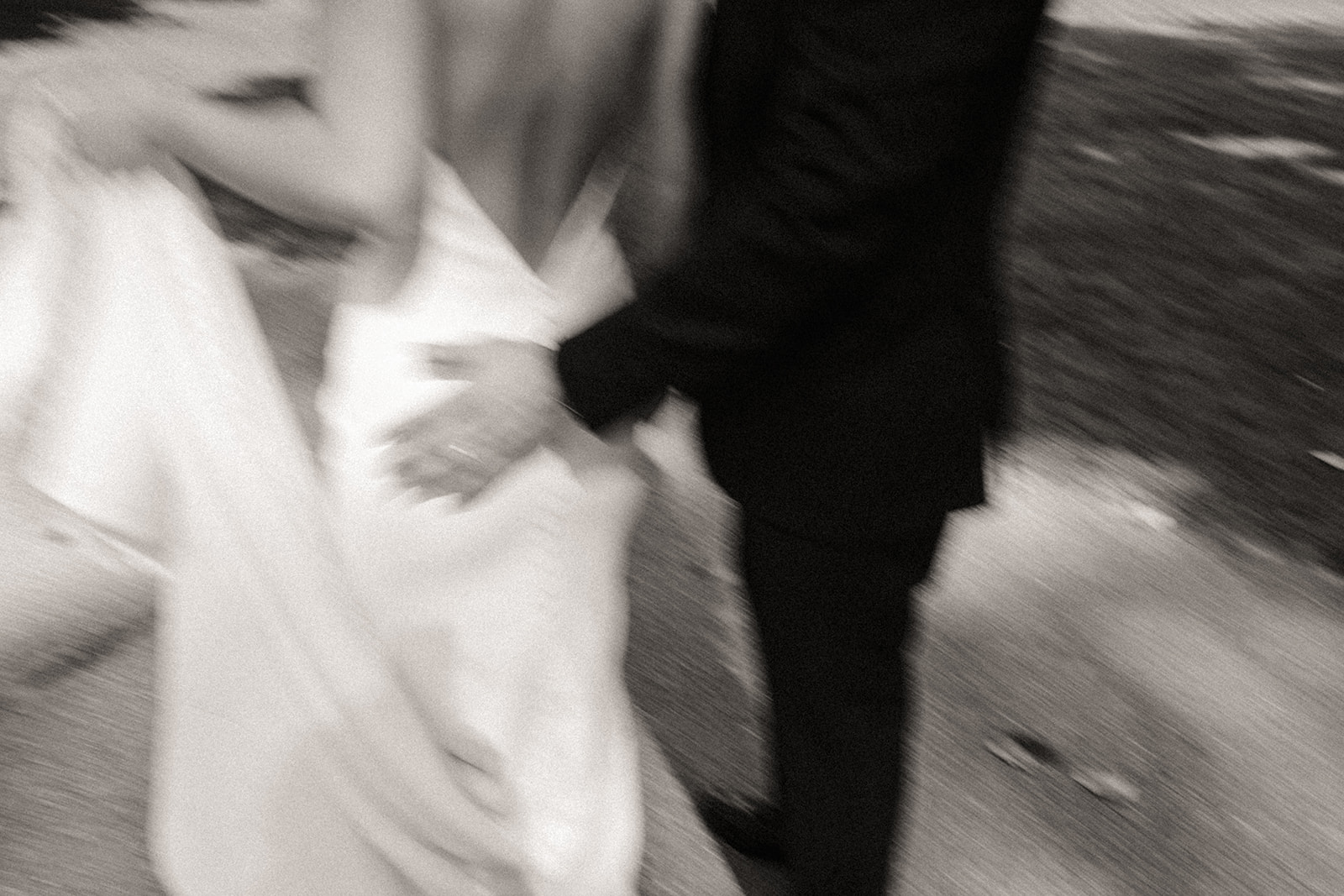 Blurry black and white photo of a bride and groom walking