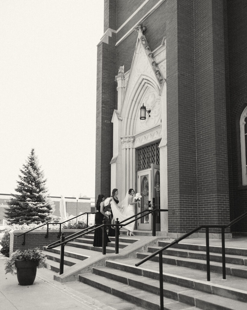 Black and white photo of a bride and her bridesmaids walking into a church