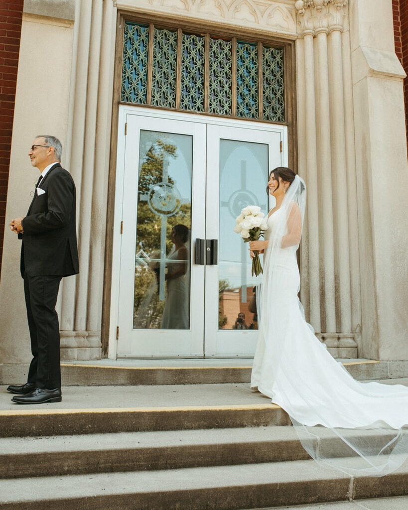 Bride standing on the church steps about to share a first look with her father