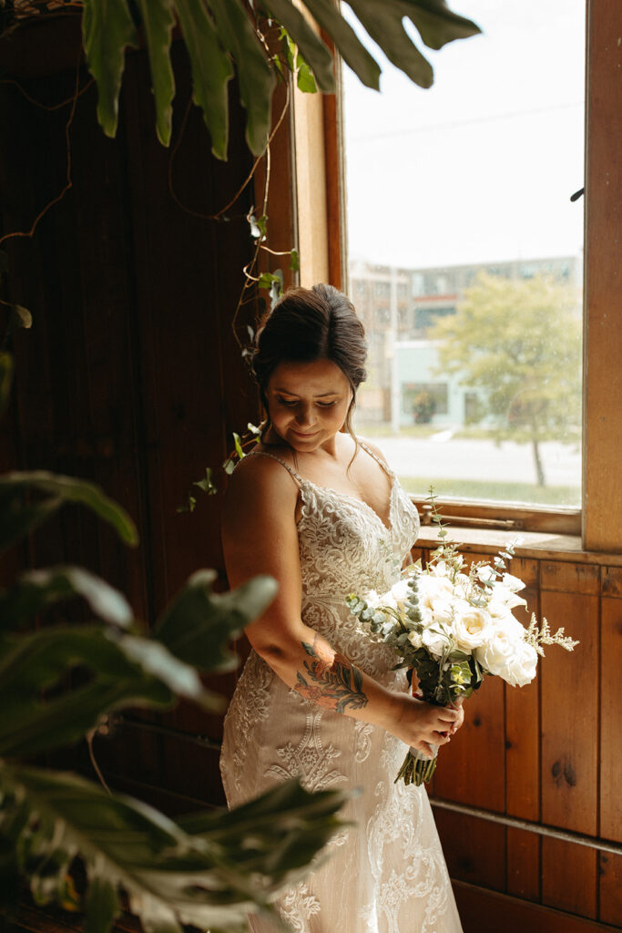 Bride posing for portraits next to a window