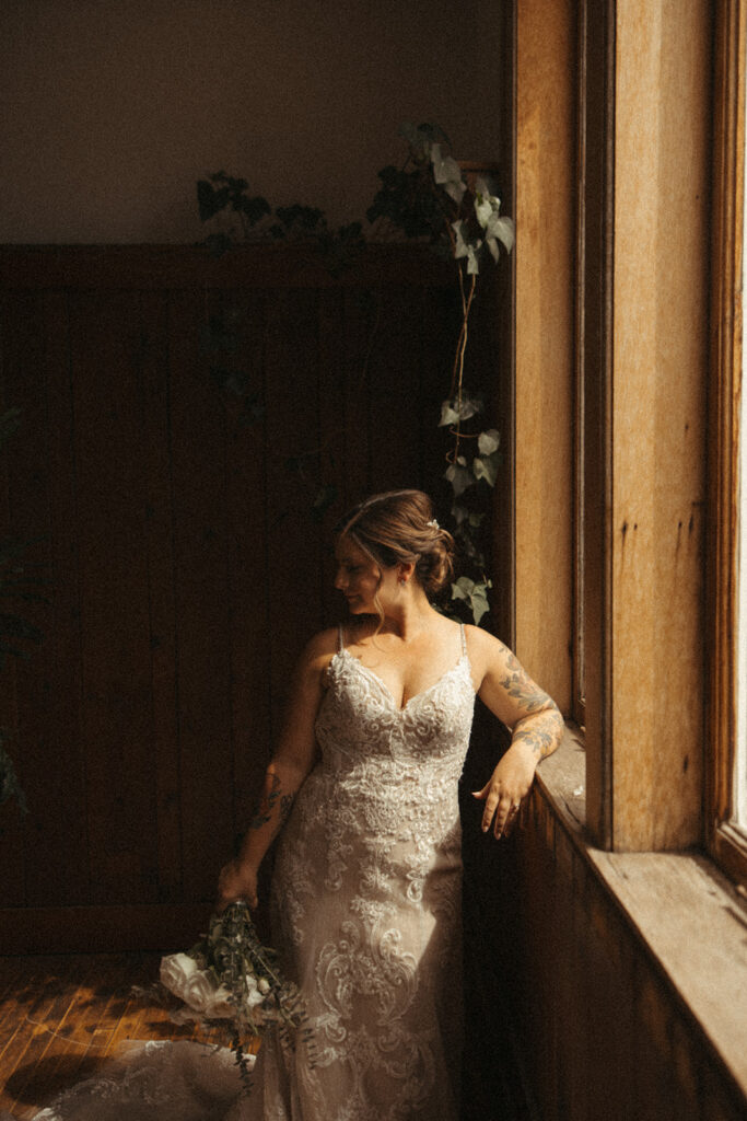 Bride posing for portraits next to a window.