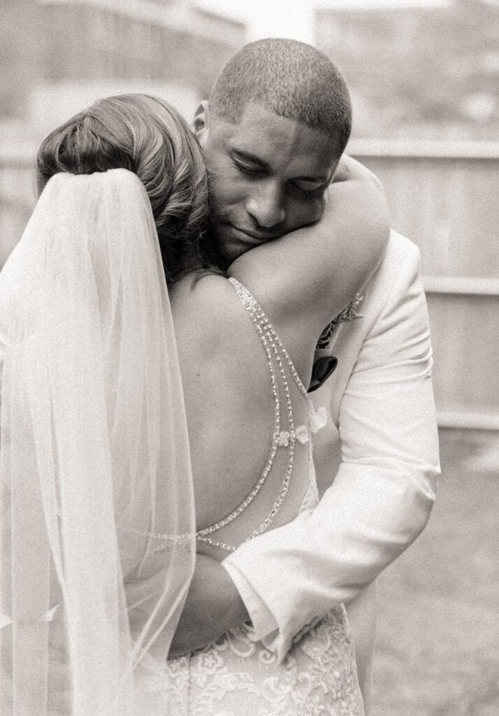 Black and white photo of a bride and groom sharing an intimate moment during their first looks outside of Jam Handy wedding venue in Detroit, Michigan