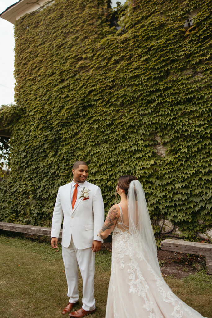 Groom turning around to see his bride for the first time outside of Jam Handy wedding venue in Detroit, Michigan