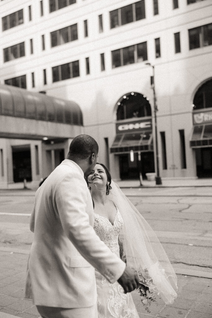 Black and white photo of a bride and groom walking in downtown Detroit.
