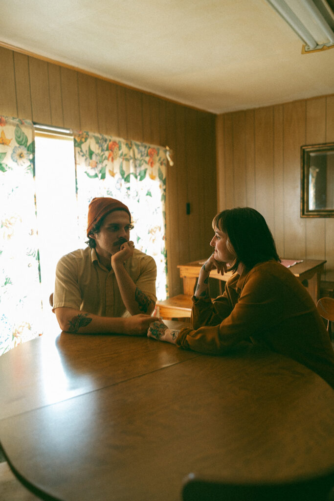 Man and woman holding hands at a kitchen table during their at-home vintage couple photoshoot in Michigan