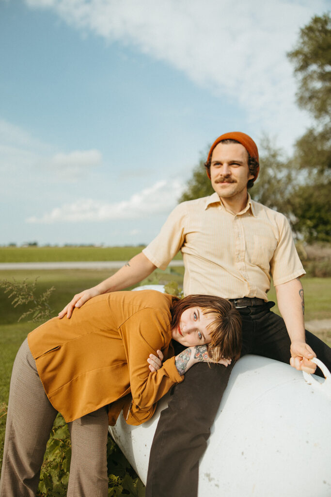 Couple posing against a propane tank outside during their at-home vintage couple photoshoot in Michigan