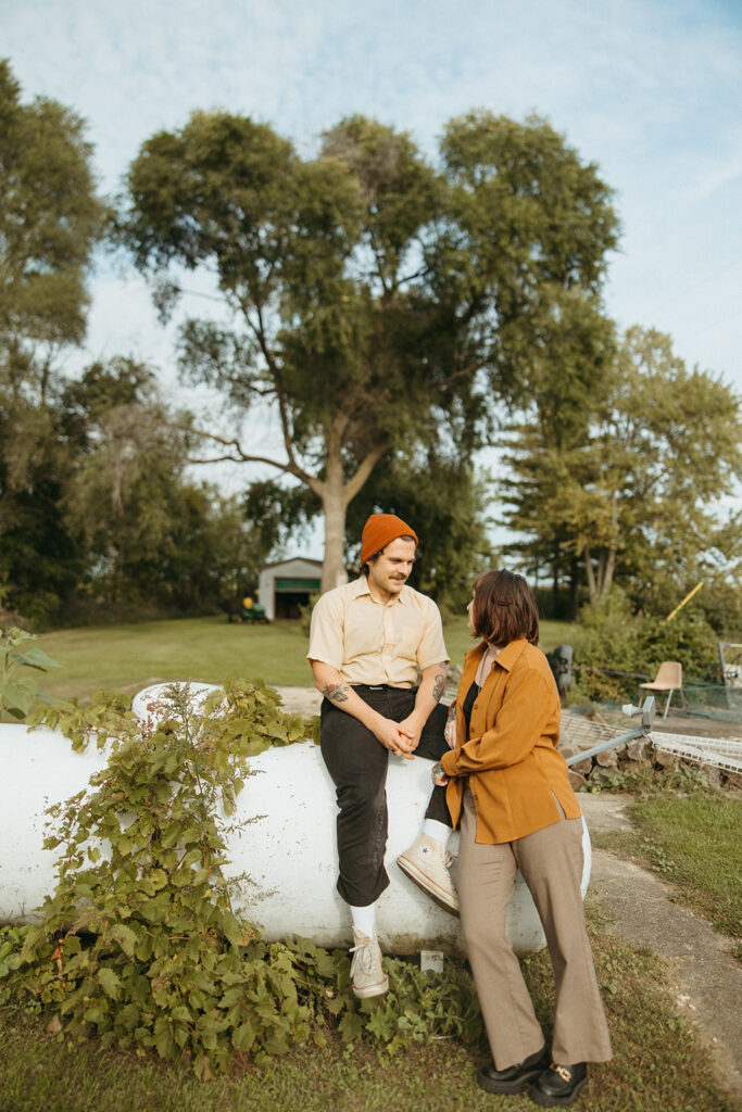 Couple posing against a propane tank outside during their at-home vintage couple photoshoot in Michigan