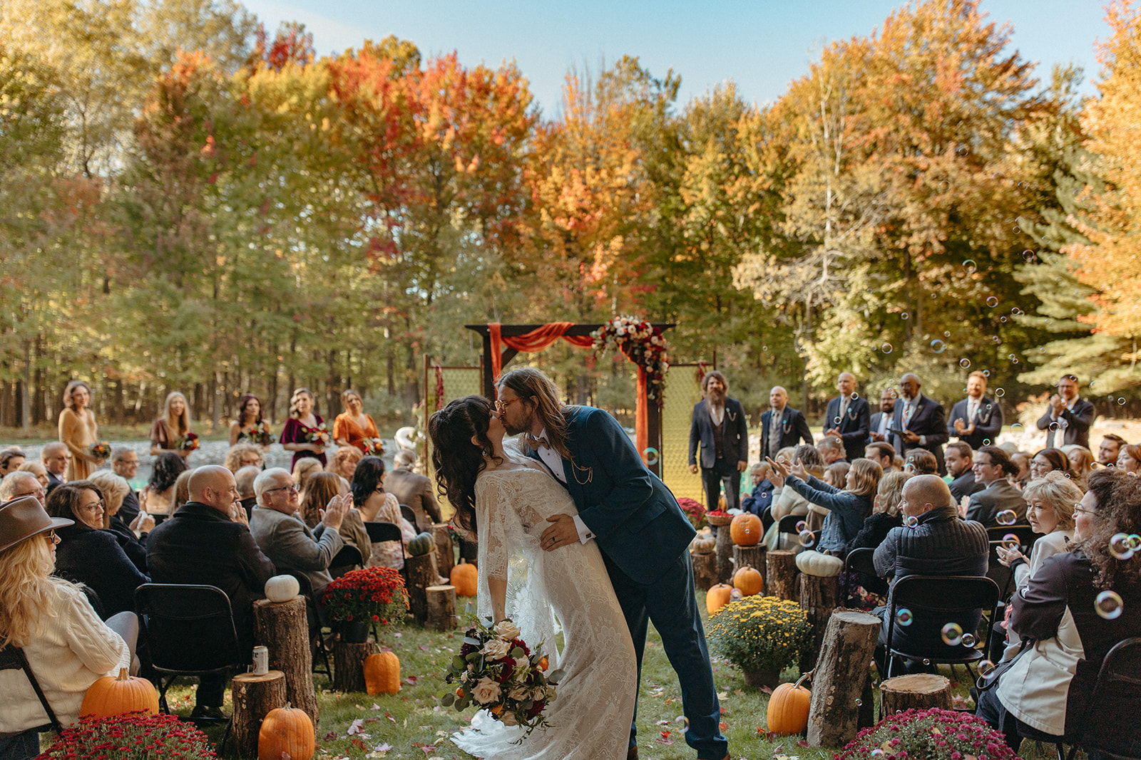 Bride and groom kissing at the end of the aisle during their fall backyard wedding in Michigan