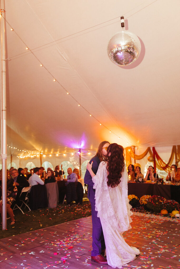 Bride and groom dancing underneath a disco during their intimate fall backyard wedding in Michigan