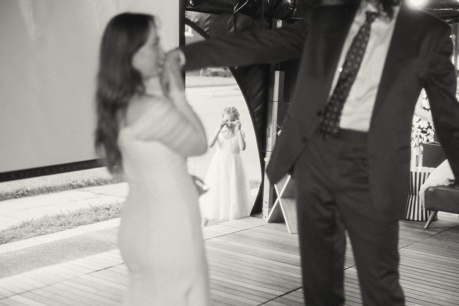 Black and white photo of a bride and grooms first dance with a flower girl watching them