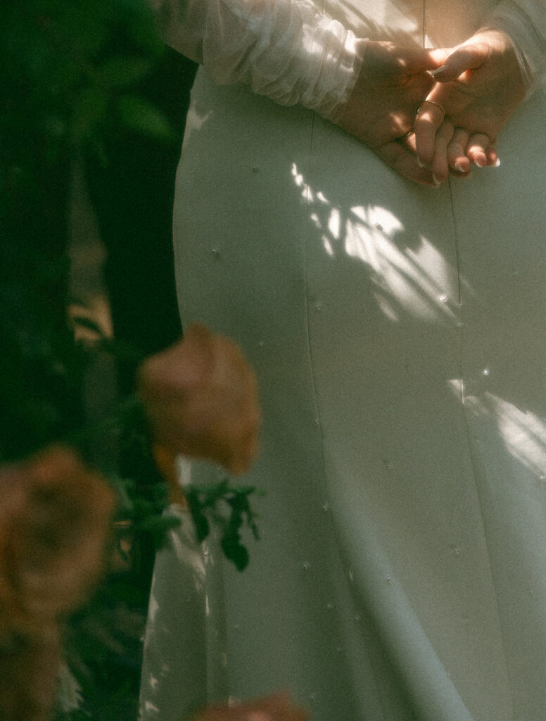 Bride holding her hands behind her band during her Stony Creek Metropark wedding ceremony in Detoit, Michigan