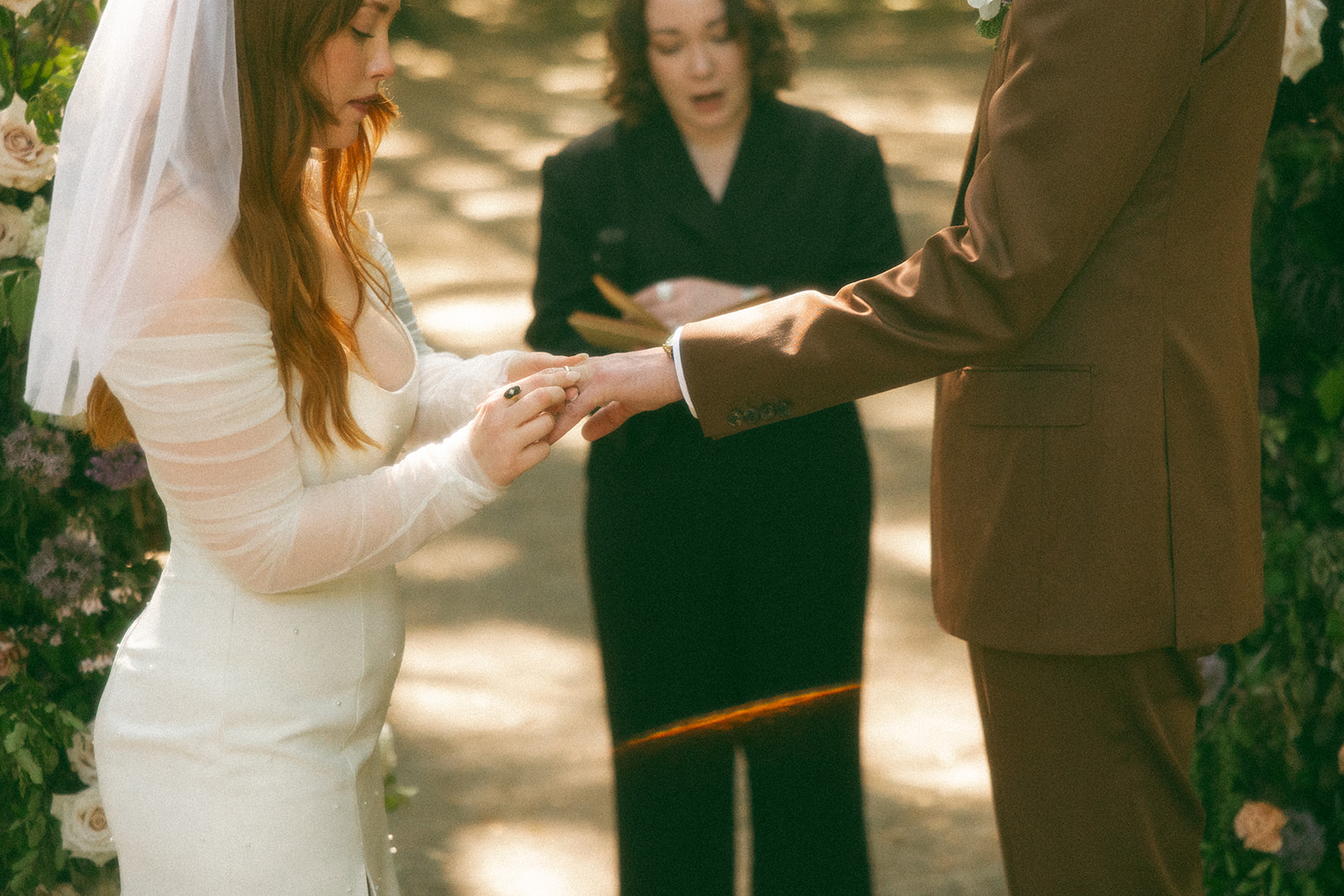 Bride putting a ring on her grooms finger during their outdoor wedding ceremony