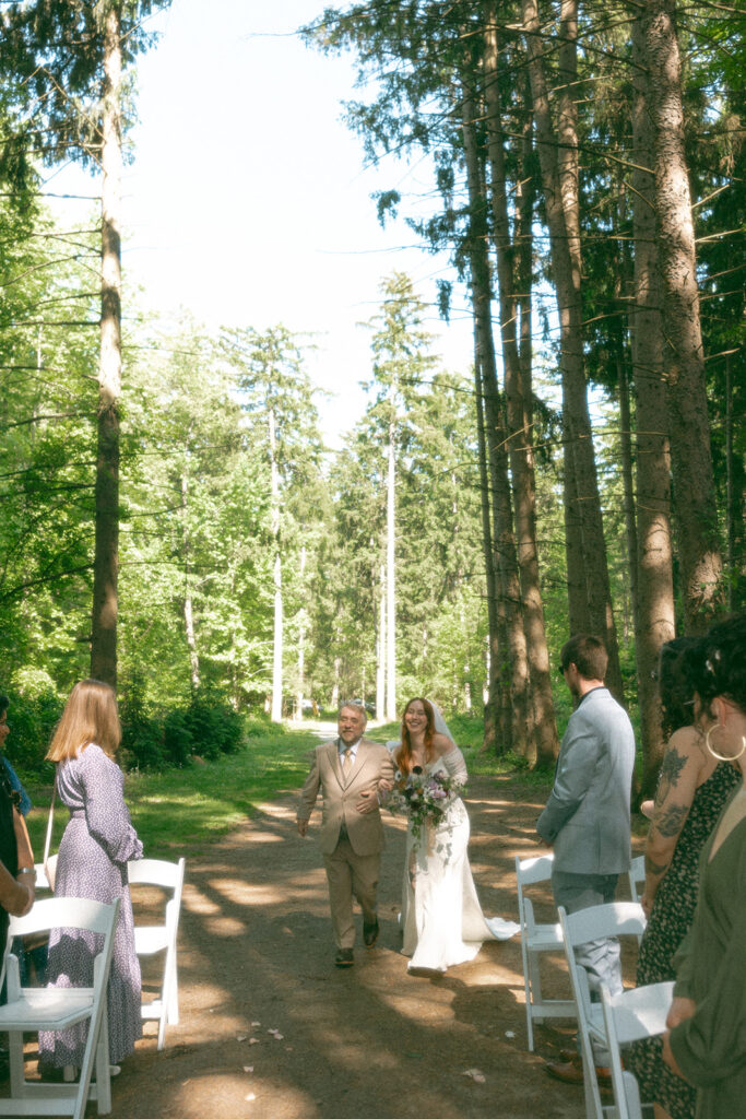 Bride being walked down the aisle by her father for her Stony Creek Metropark wedding in Detroit, Michigan