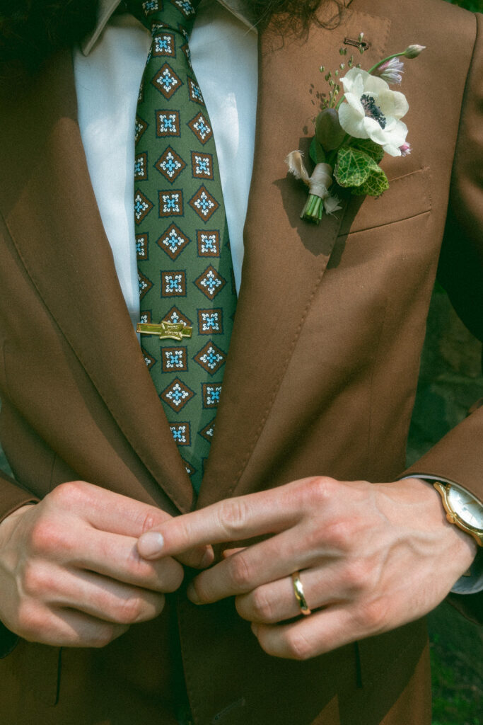 Groom wearing a brown suit with a patterned green tie 