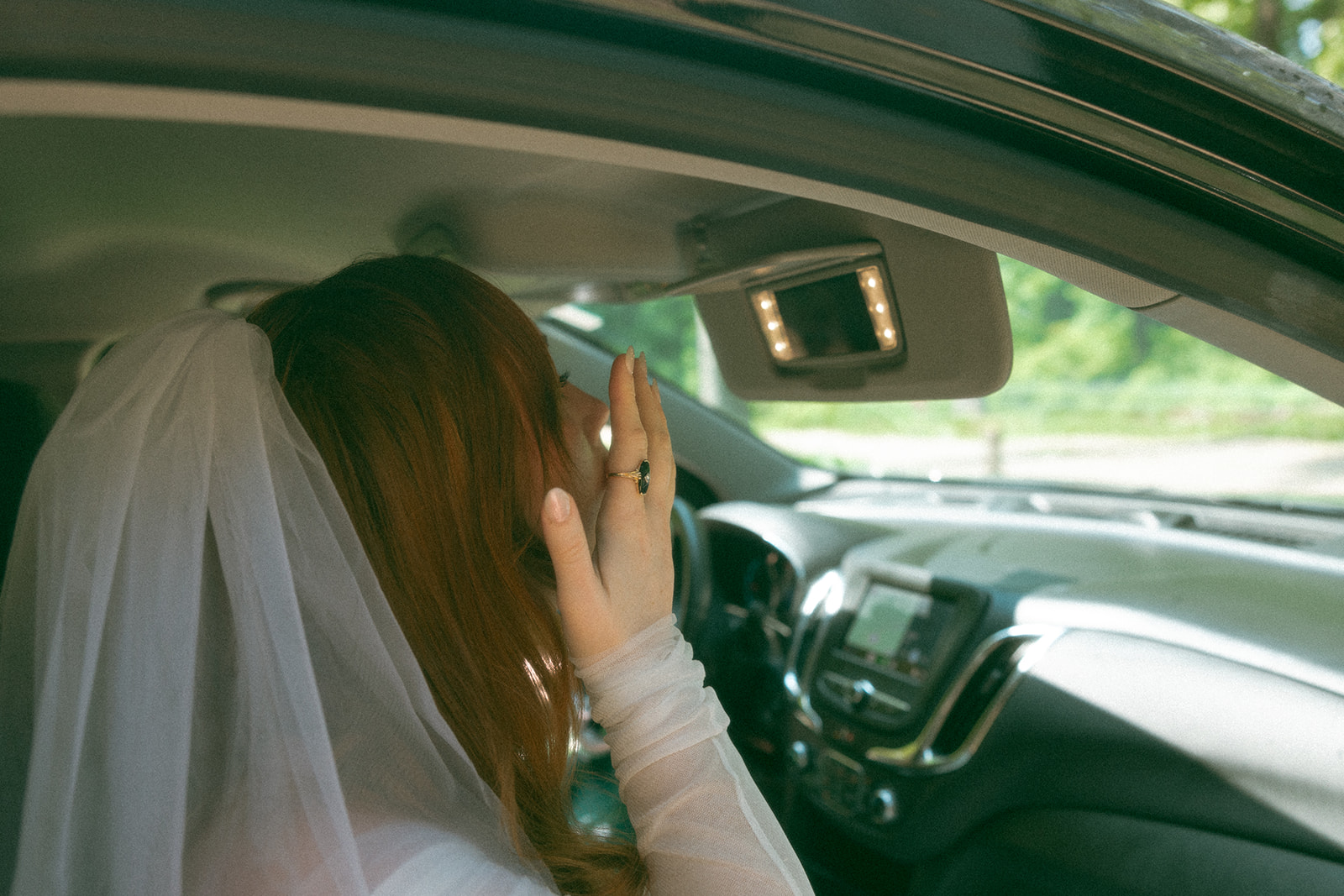 Bride checking her makeup in the car mirror before first looks