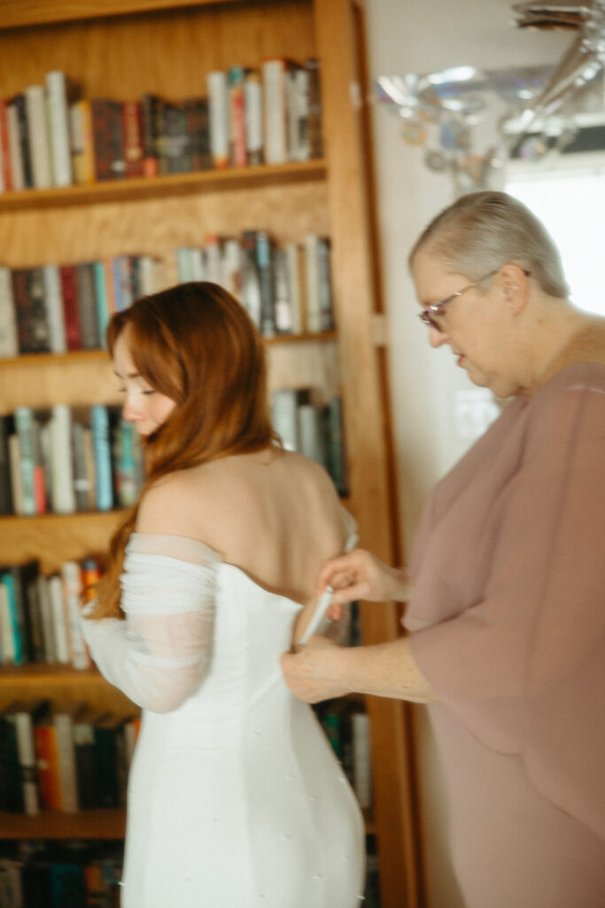 Brides mother zipping her wedding dress up