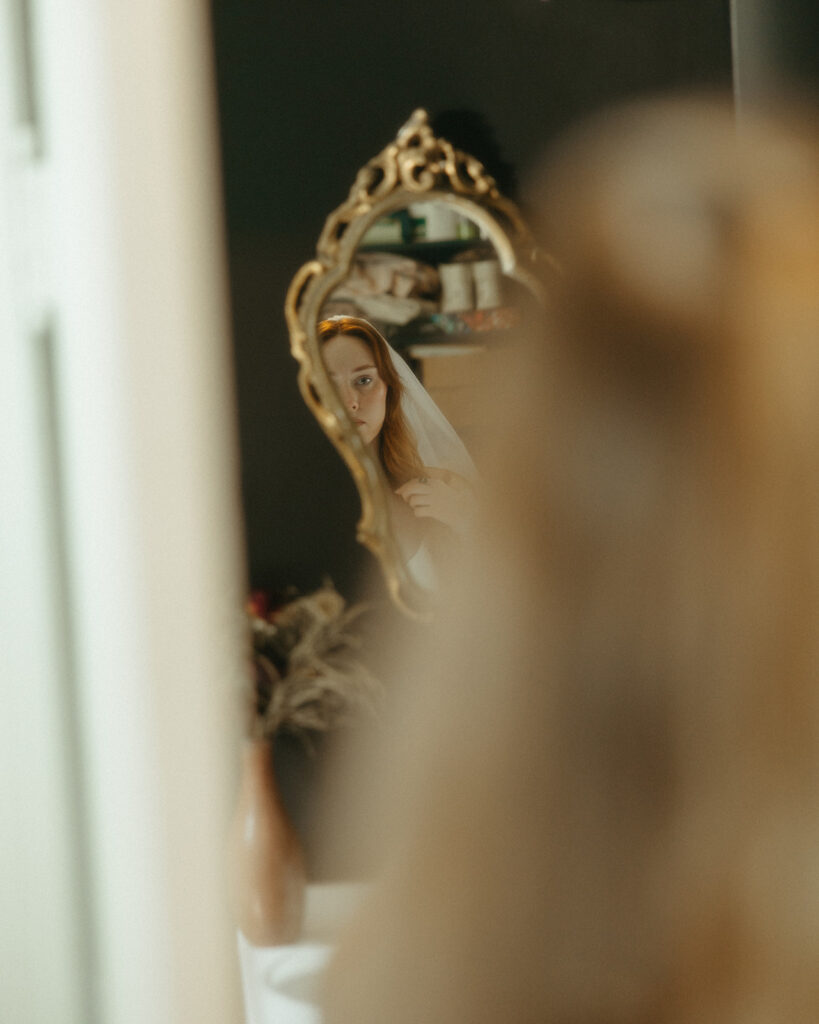 Bride looking at herself in the mirror before her Detroit wedding