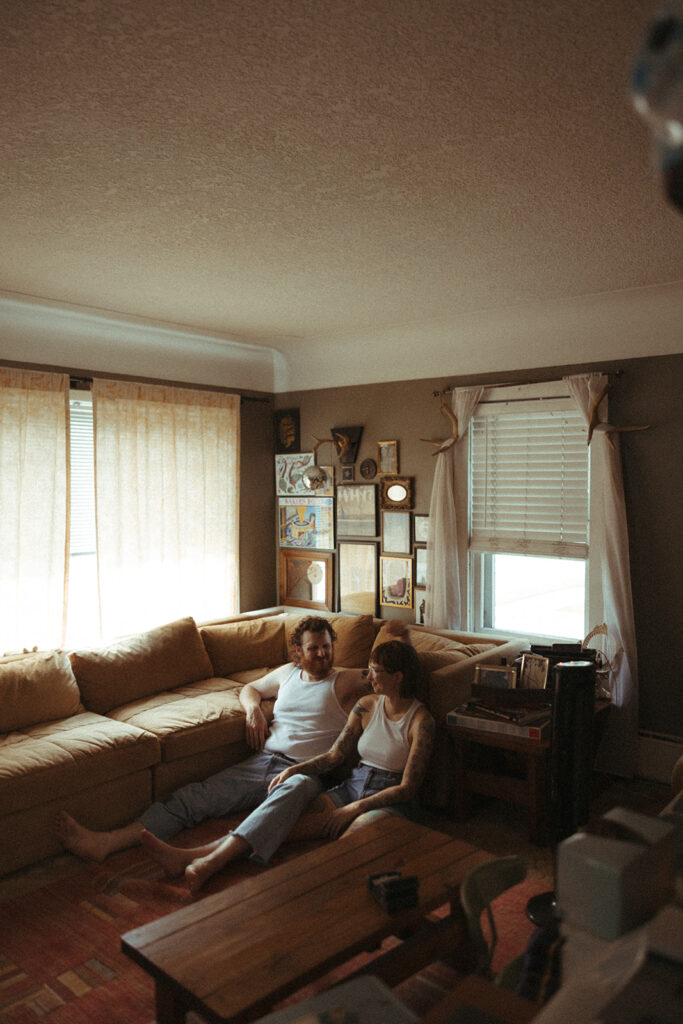 Man and woman leaning against their couch during their at-home couples photoshoot in Grand Rapids, Michigan