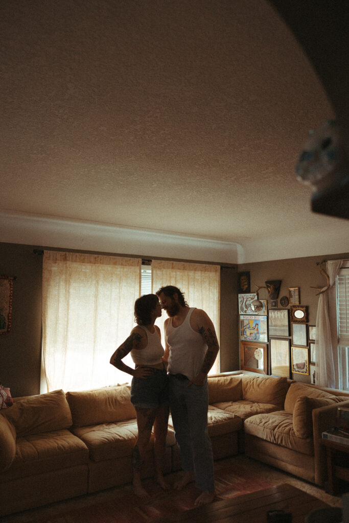 Man and woman posing for photos in their living room during their at-home couples photoshoot