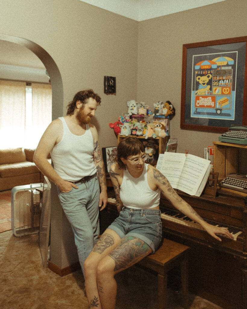 Man and woman posing with their piano for their at-home couples photoshoot