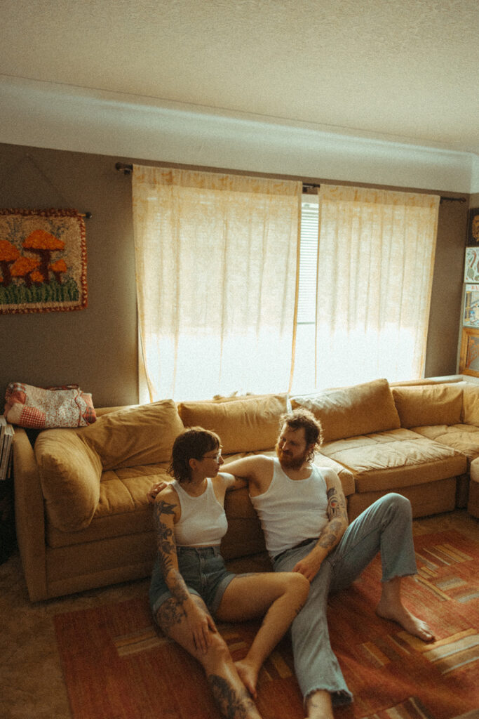 Couple sitting on the floor of their living room together for their at-home couples photoshoot