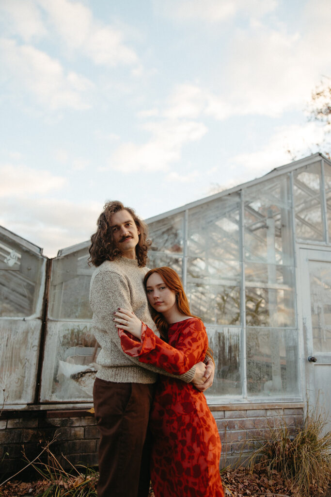 Man and woman posing in front of a Greenhouse for their Belle Isle engagement photos in Detroit, Michigan