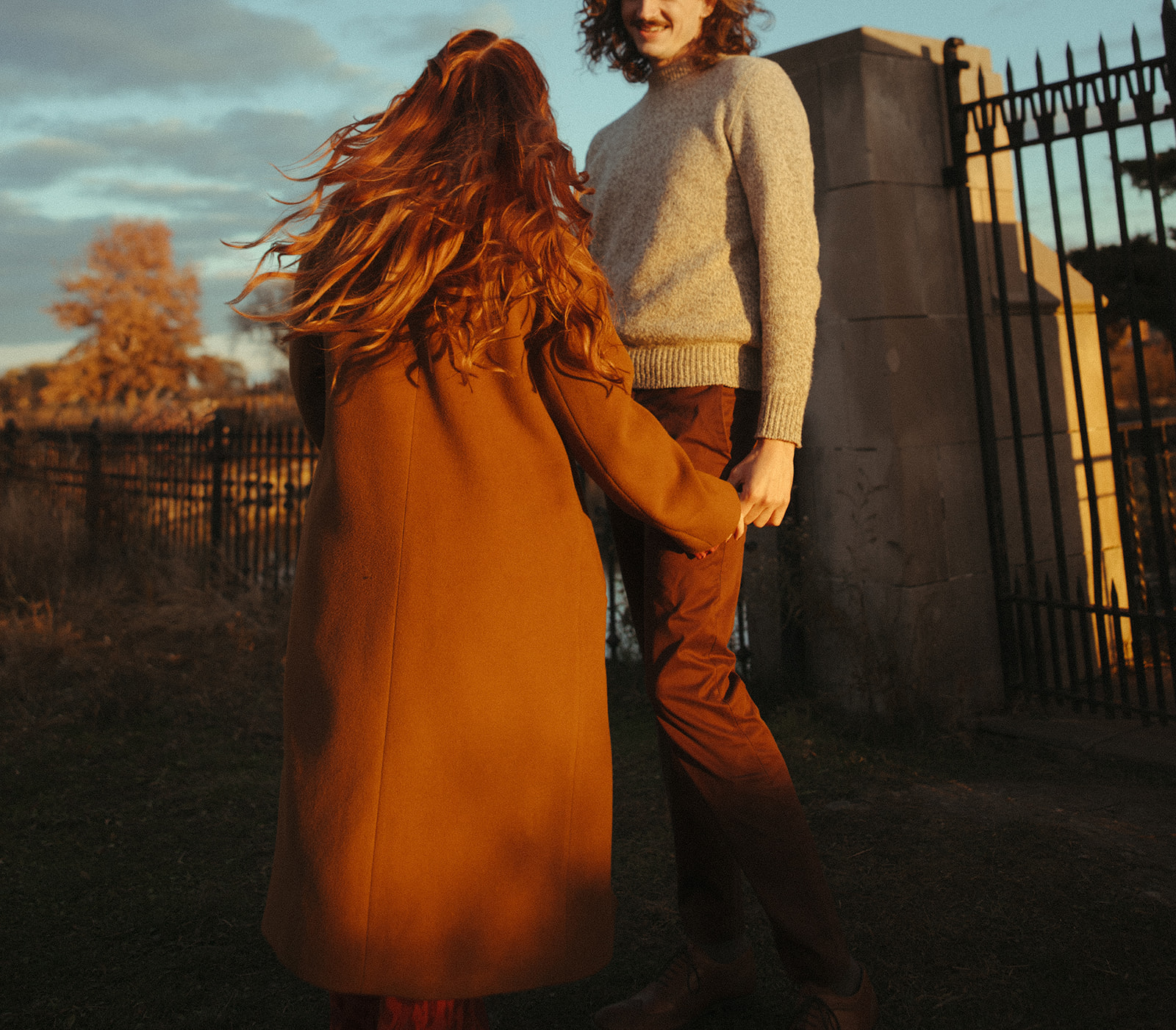 Man and woman having fun during their fall sunset Belle Isle engagement photos in Detroit, Michigan